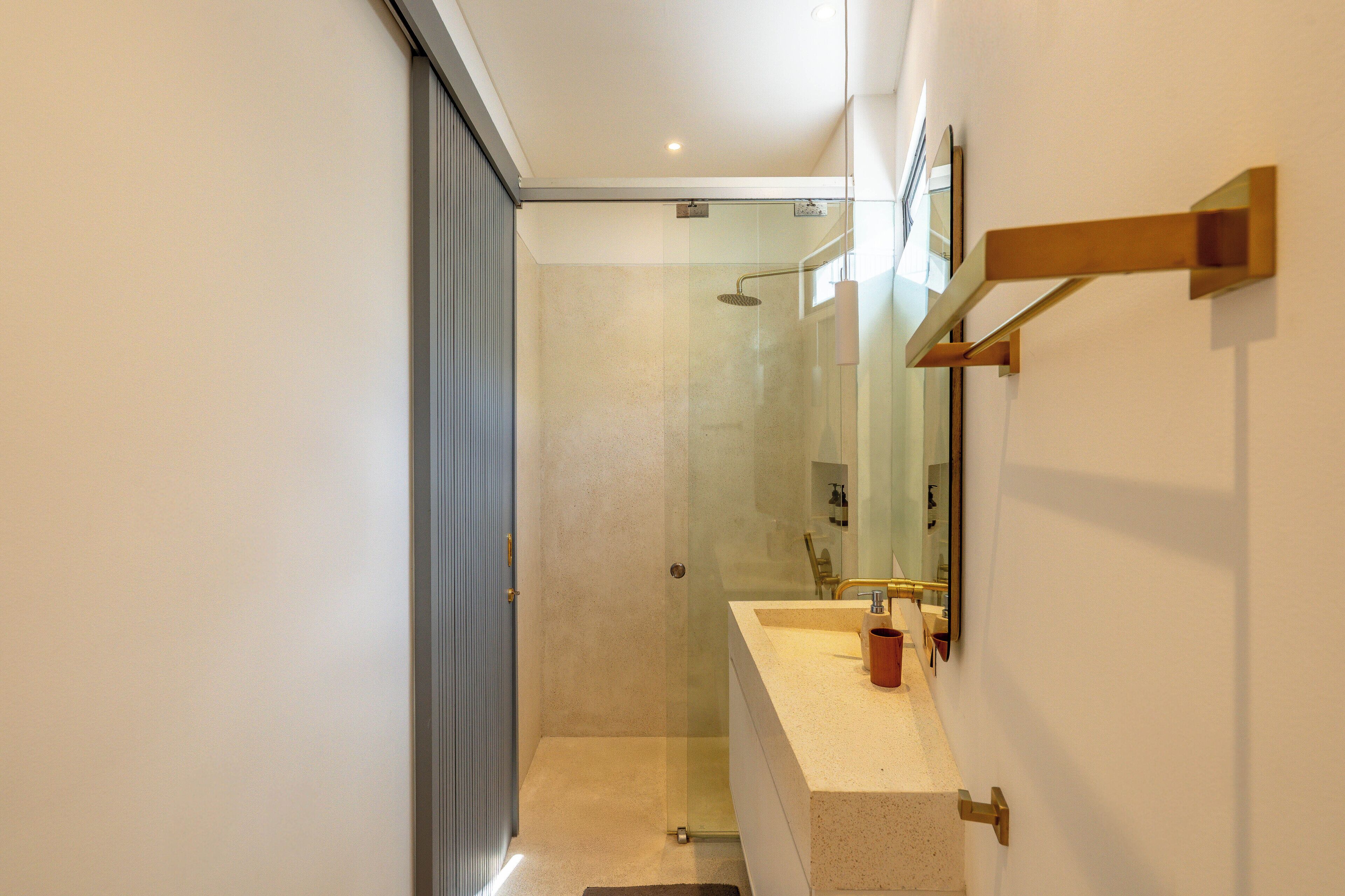 Un baño moderno con cabina de ducha de vidrio, lavabo con espejo y toallero.