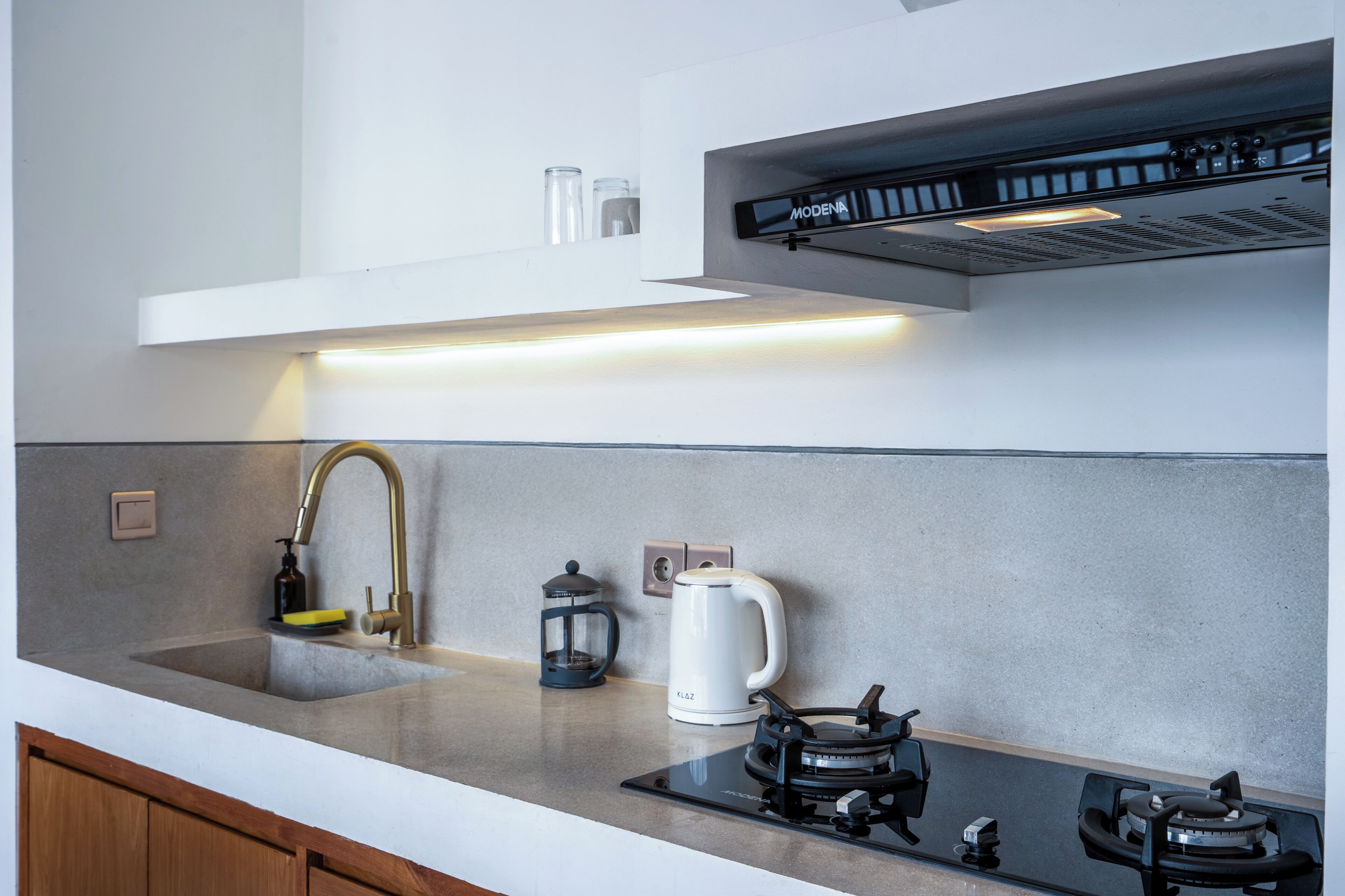 A modern kitchen with a stainless steel sink, a gas stove, a coffee maker, and a kettle.