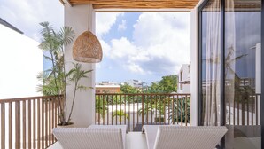 A balcony with two white cushioned chairs, a wicker hanging light, and a view of the cityscape. - Sore Pererenan Luxury Suites by Betterplace (Pererenan)