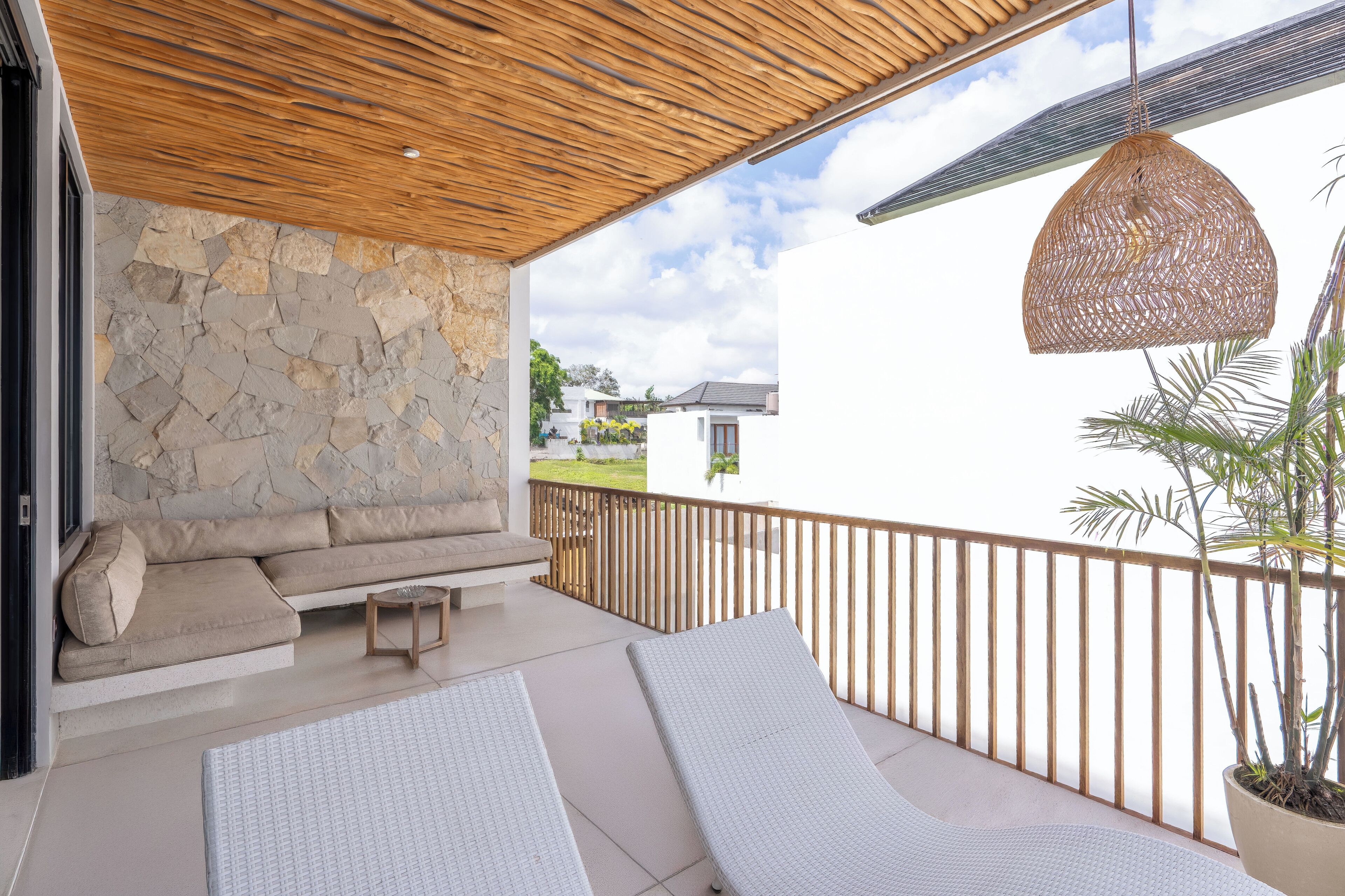 Un balcon doté d’un mur en pierre, d’un plafond en bois et d’un luminaire suspendu en osier.