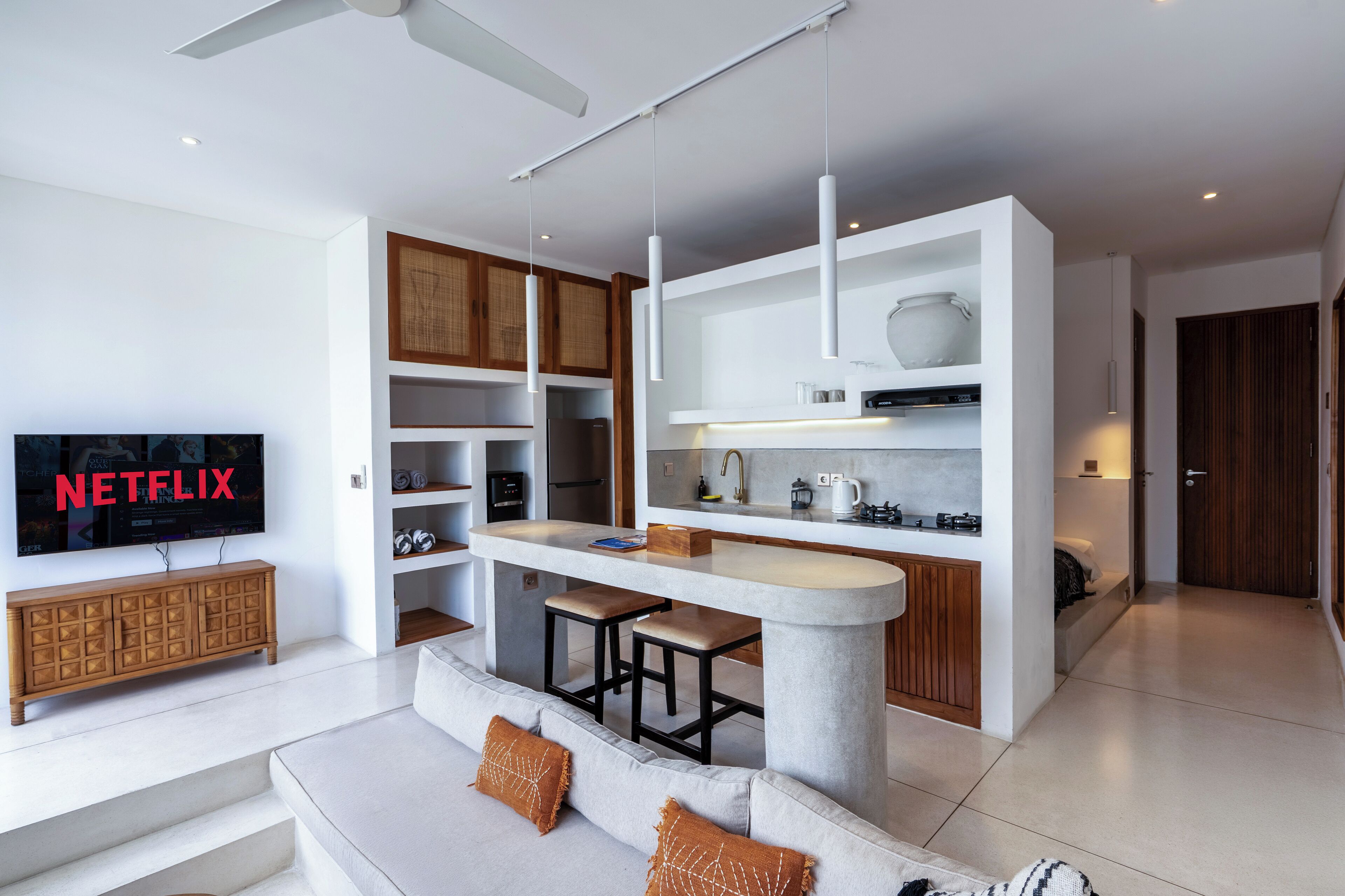 Een moderne keuken met een centraal eiland, ingebouwde kasten en een flatscreen televisie waarop 'NETFLIX' wordt weergegeven.