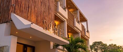 A modern building with a large sign, balconies, and a stone facade.