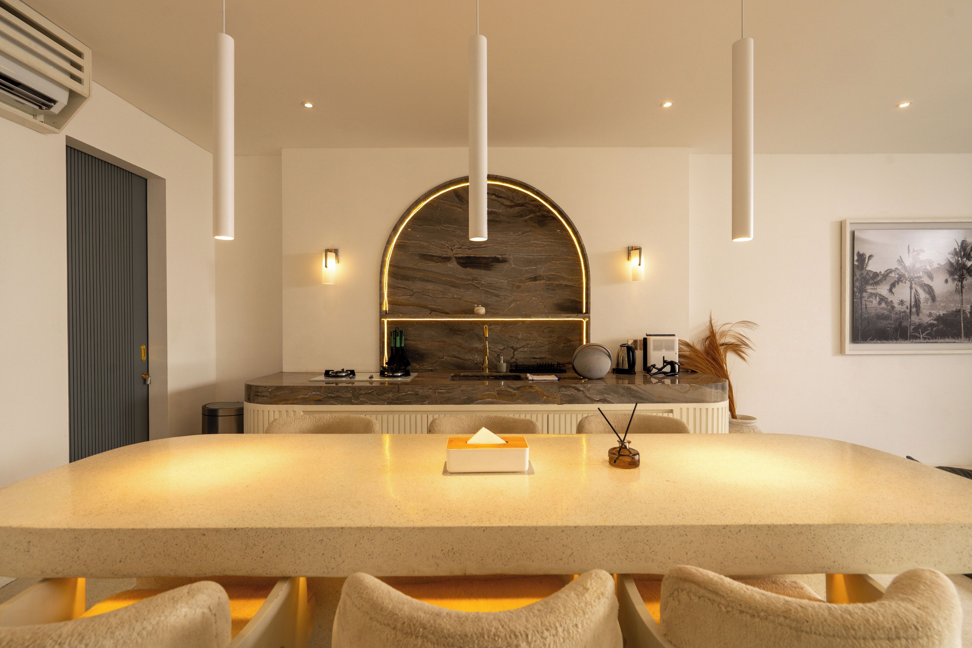 Una cocina moderna con una isla grande, luces colgantes y un protector contra salpicaduras de mármol.
