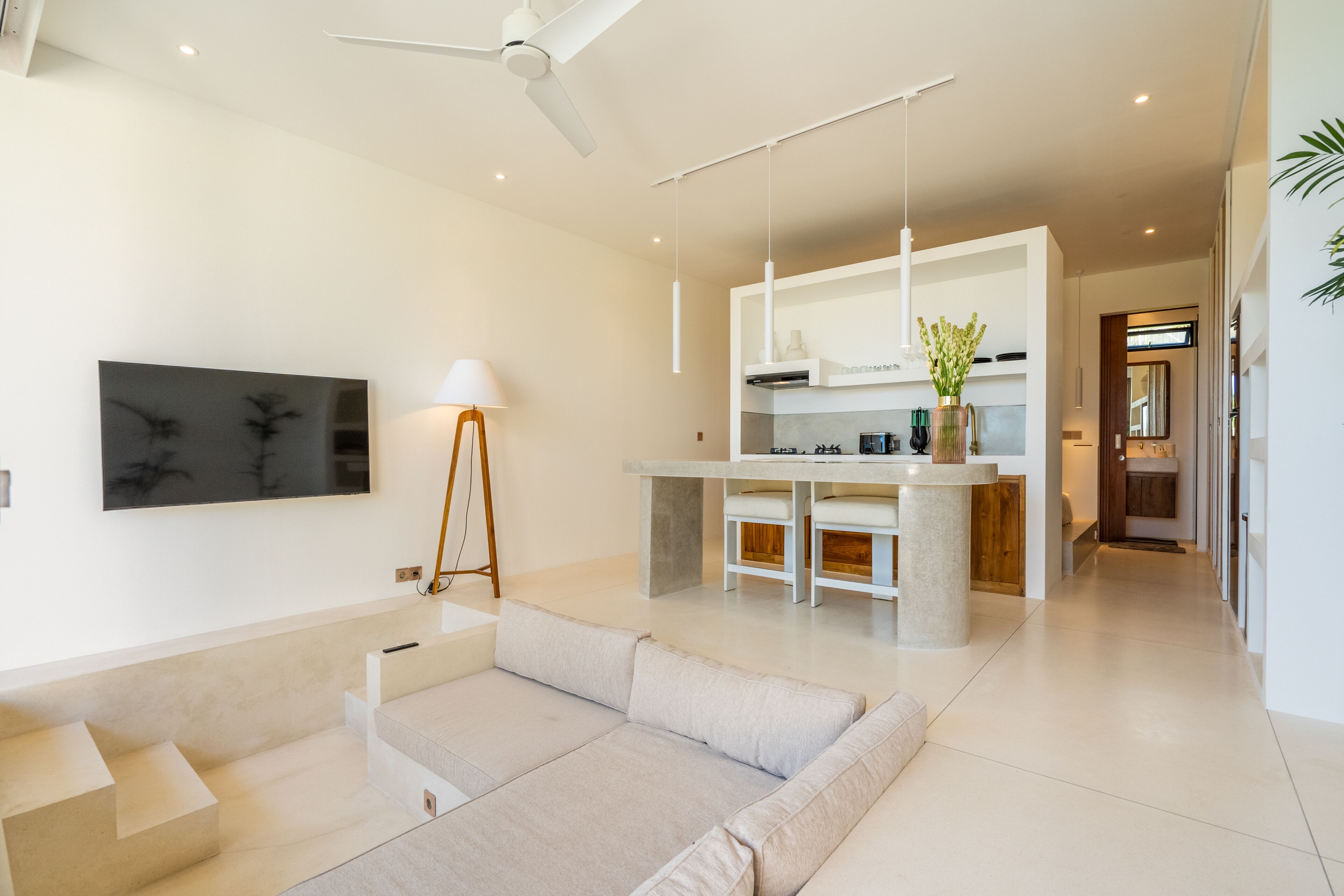 Ein modernes Wohnzimmer mit Sofa, Couchtisch und Essbereich, im Hintergrund eine Küche.