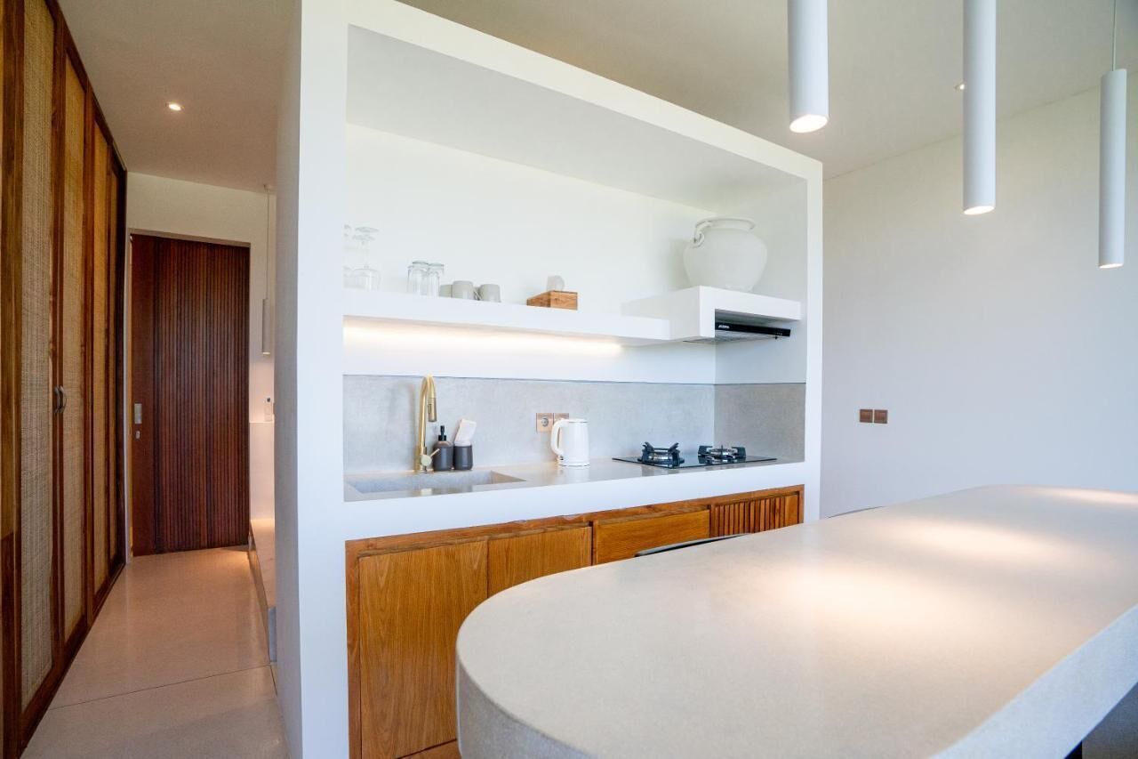 A modern kitchen with white cabinetry, a large island, and built-in shelves.