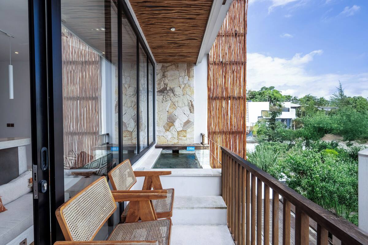 Un balcon avec un mur en pierre, une balustrade en bois et une vue sur un jardin.