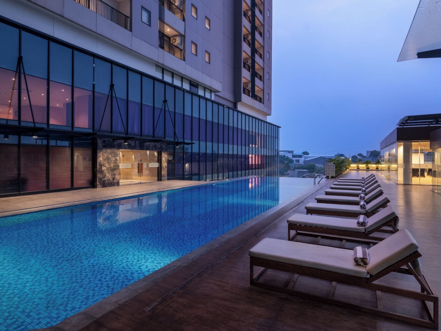 A modern hotel with a swimming pool and lounge chairs.