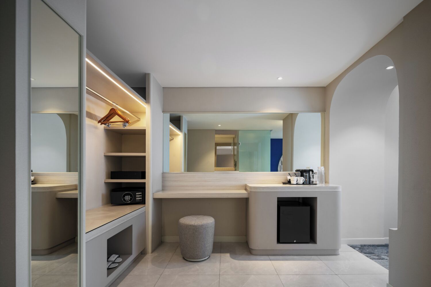 Une salle de bain moderne avec un grand miroir, des étagères intégrées, un meuble-lavabo et une petite poubelle.