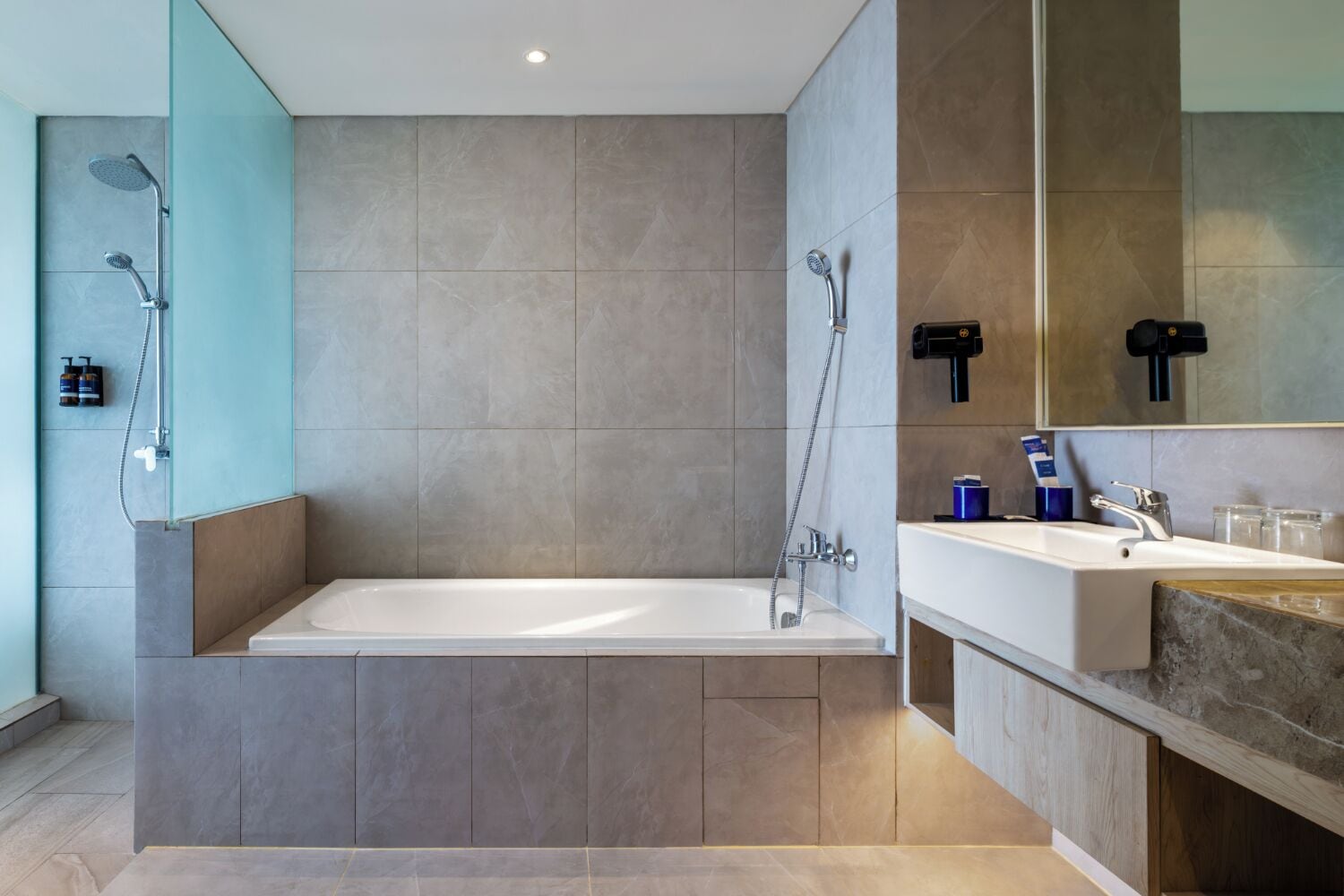 Un baño moderno con una bañera independiente, cabina de ducha con mampara de vidrio y tocador con lavabo y espejo.