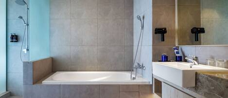 Un baño moderno con una bañera independiente, cabina de ducha con mampara de vidrio y tocador con lavabo y espejo.