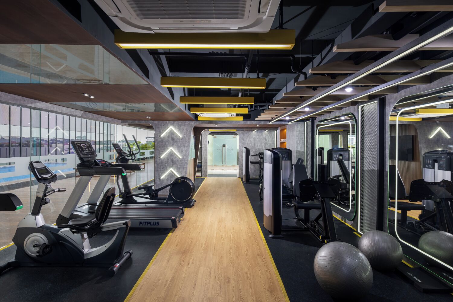 Une salle de sport moderne équipée de machines de cardio, de matériel de musculation et de ballons d’exercice.