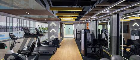 A modern gym with cardio machines, weightlifting equipment, and exercise balls.
