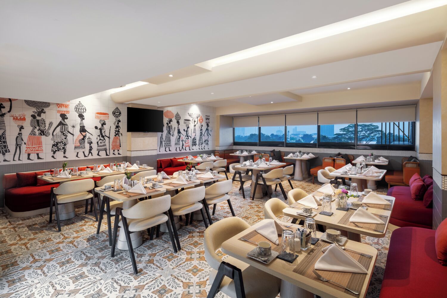 A restaurant with multiple dining tables and booths, a patterned floor, and a city view through large windows.
