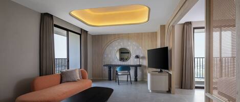 A modern hotel room with a sofa, a dining table with chairs, a TV, and a balcony with a view.
