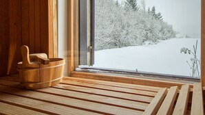 A wooden sauna with a bench and a wooden bucket, a window with a snowy landscape view. - Relax & Play by Interhome (Čabar)