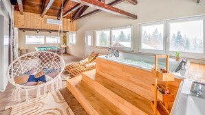 A modern spa room with a wooden bench, a hanging chair, a pool table, and a large window with a view of trees. - Relax & Play by Interhome (Čabar)