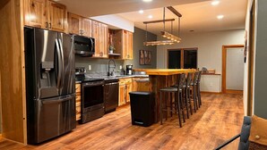 Une cuisine moderne avec des meubles en bois, des appareils électroménagers en acier inoxydable et un îlot central doté de tabourets de bar.