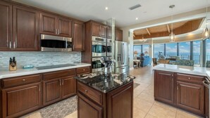 A modern kitchen with dark wood cabinets, stainless steel appliances, and a large island. - Penthouse, Stunning view, beach front, private (Panama City Beach)