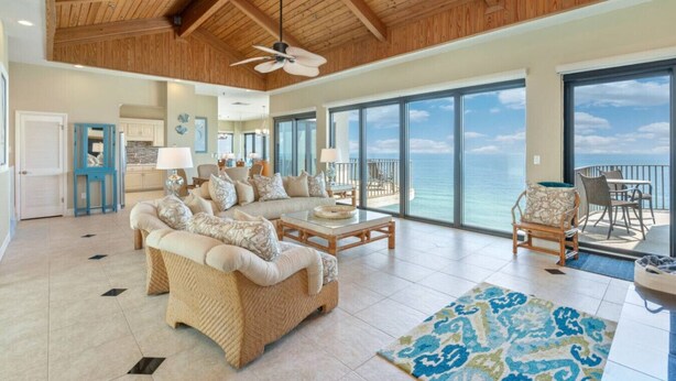 A spacious living room with a large sofa set, a coffee table, and a view of the ocean through large windows. - Penthouse, Stunning view, beach front, private (Panama City Beach)