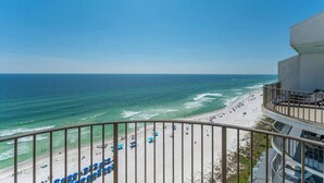 A beach view from a balcony with a railing, a clear sky, and a sandy beach with umbrellas. - Penthouse, Stunning view, beach front, private (Panama City Beach)