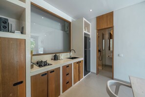 A modern kitchen with a gas stove, sink, and a built-in oven. - Dreamscape Haven  (Canggu)