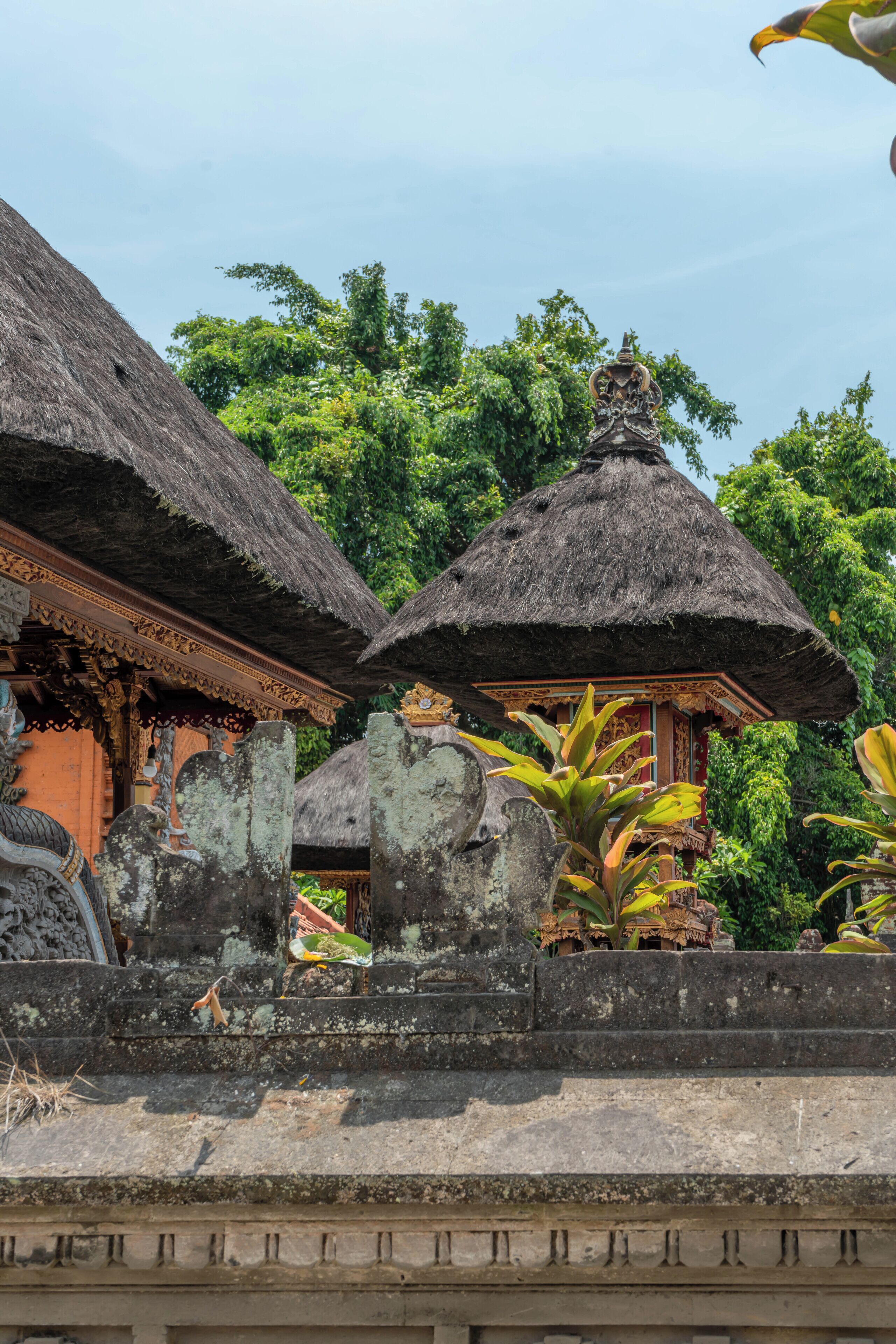 Traditional thatched-roof structures with intricate carvings, surrounded by lush greenery.