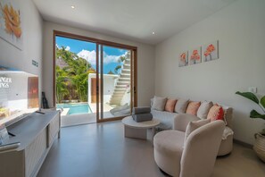 A modern living room with a pool, a staircase leading to a balcony, and a TV on the left. - Dreamscape Haven  (Canggu)