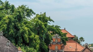 A traditional Balinese temple with a thatched roof, surrounded by lush greenery. - Dreamscape Haven  (Canggu)