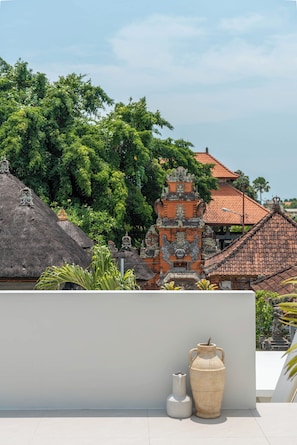 A traditional Balinese temple with a thatched roof, surrounded by lush greenery. - Dreamscape Haven  (Canggu)