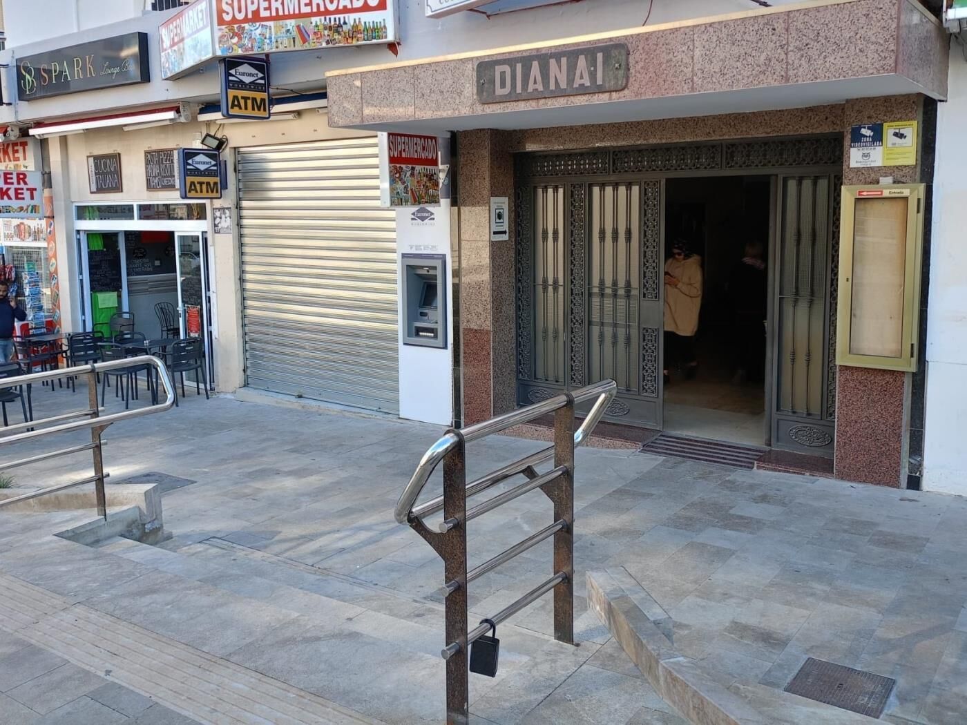 A commercial area with a closed shutter, a metal staircase, and a sign for 'DIANAI'.