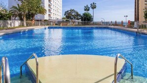 Ein Schwimmbecken mit freiem Blick auf die umliegenden Gebäude und Palmen.