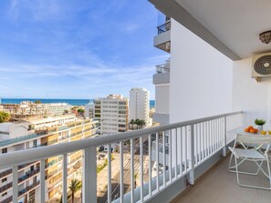 Un balcón con vista al mar y edificios circundantes.