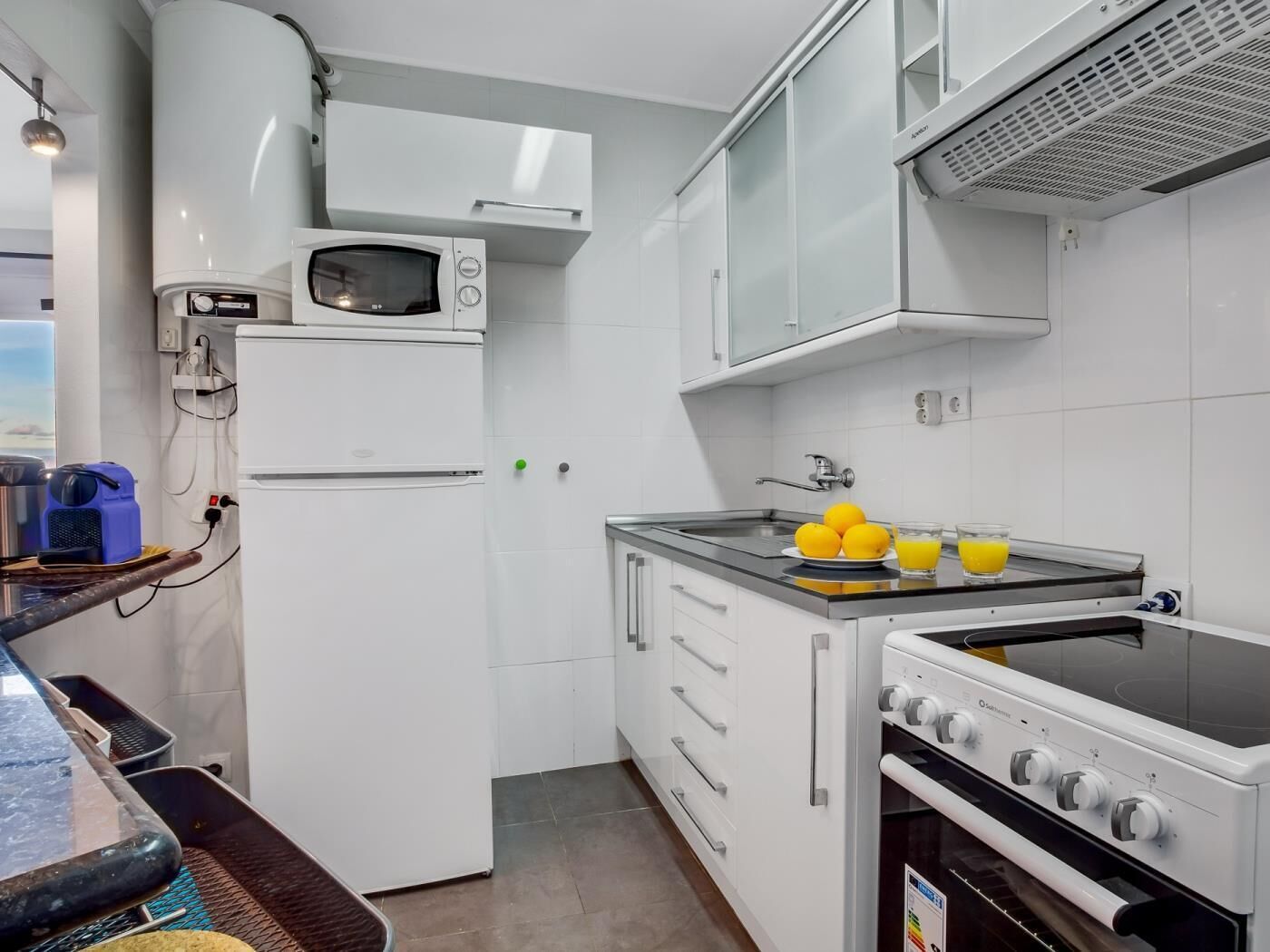 Una cucina moderna con mobili bianchi, un forno a microonde, un piano cottura e un lavello.