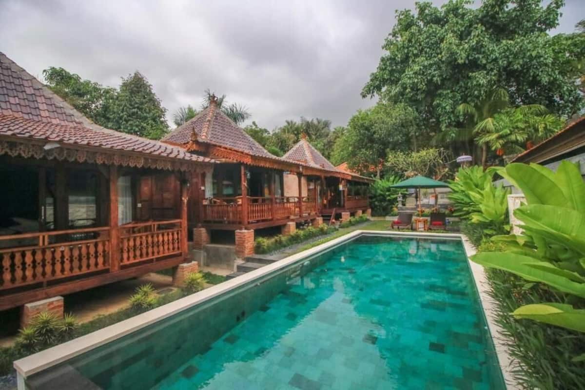 A pool area with wooden structures and lush greenery.