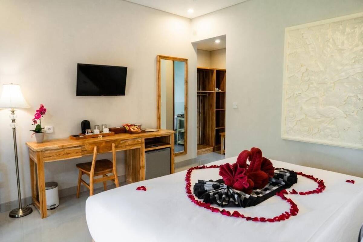 A hotel room with a bed, a desk, a chair, a TV, and a wardrobe.