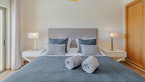 A neatly arranged bedroom with a large bed, two bedside lamps, and a ceiling light fixture.