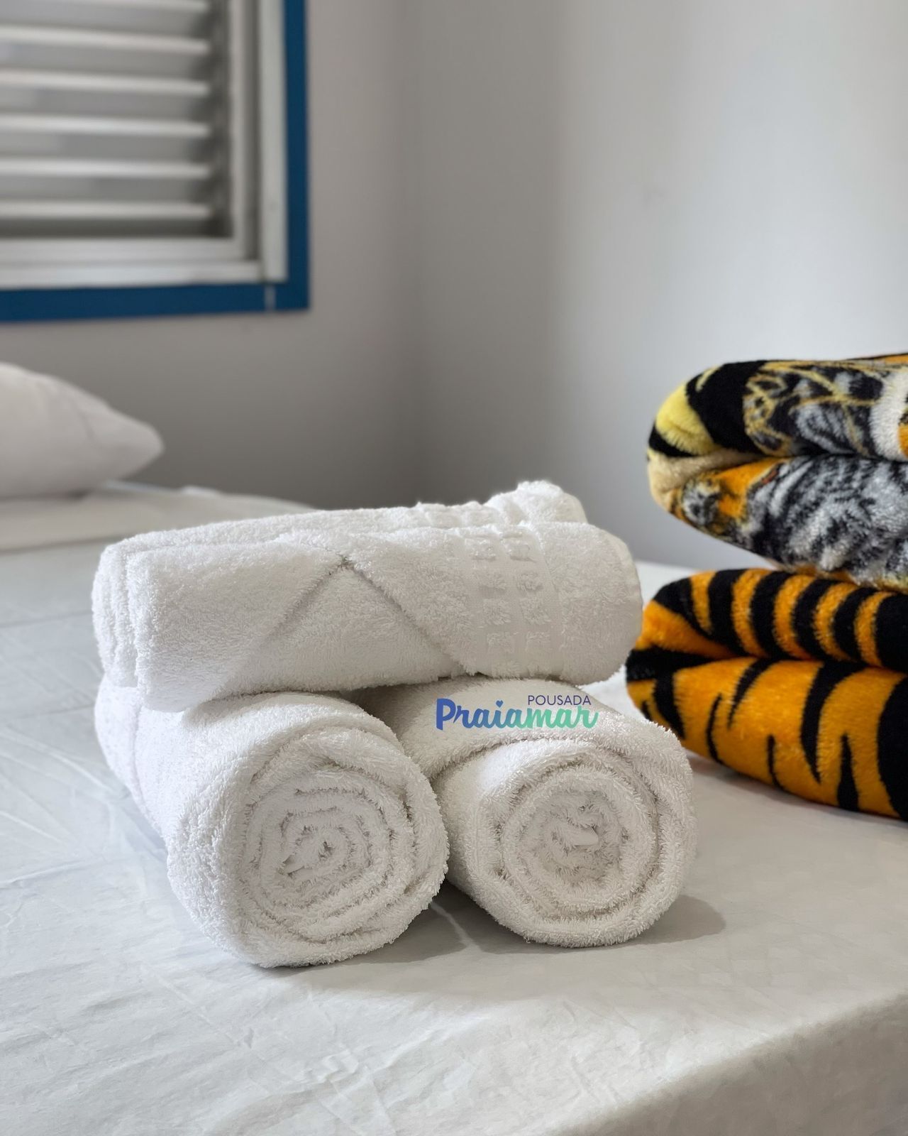 Uma cama com toalhas brancas bem dobradas e um cobertor estampado com padrão de tigre.