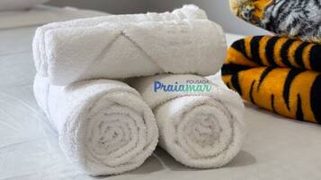 Uma cama com toalhas brancas bem dobradas e um cobertor estampado com padrão de tigre.