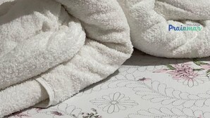 Tovalla amb forma de cigne damunt d'un llençol amb estampat floral.