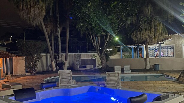 Jacuzzi amb llum blava, envoltat de mobiliari exterior i palmeres.