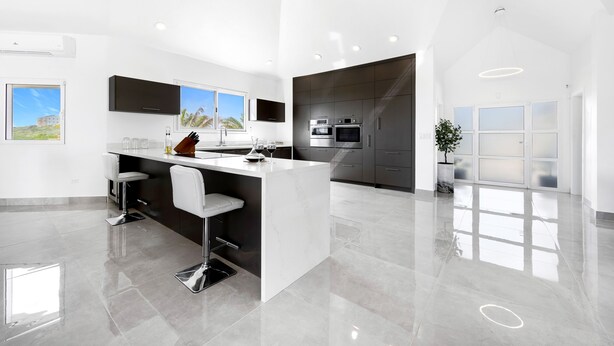 A modern kitchen with a central island, stainless steel appliances, and a large window.