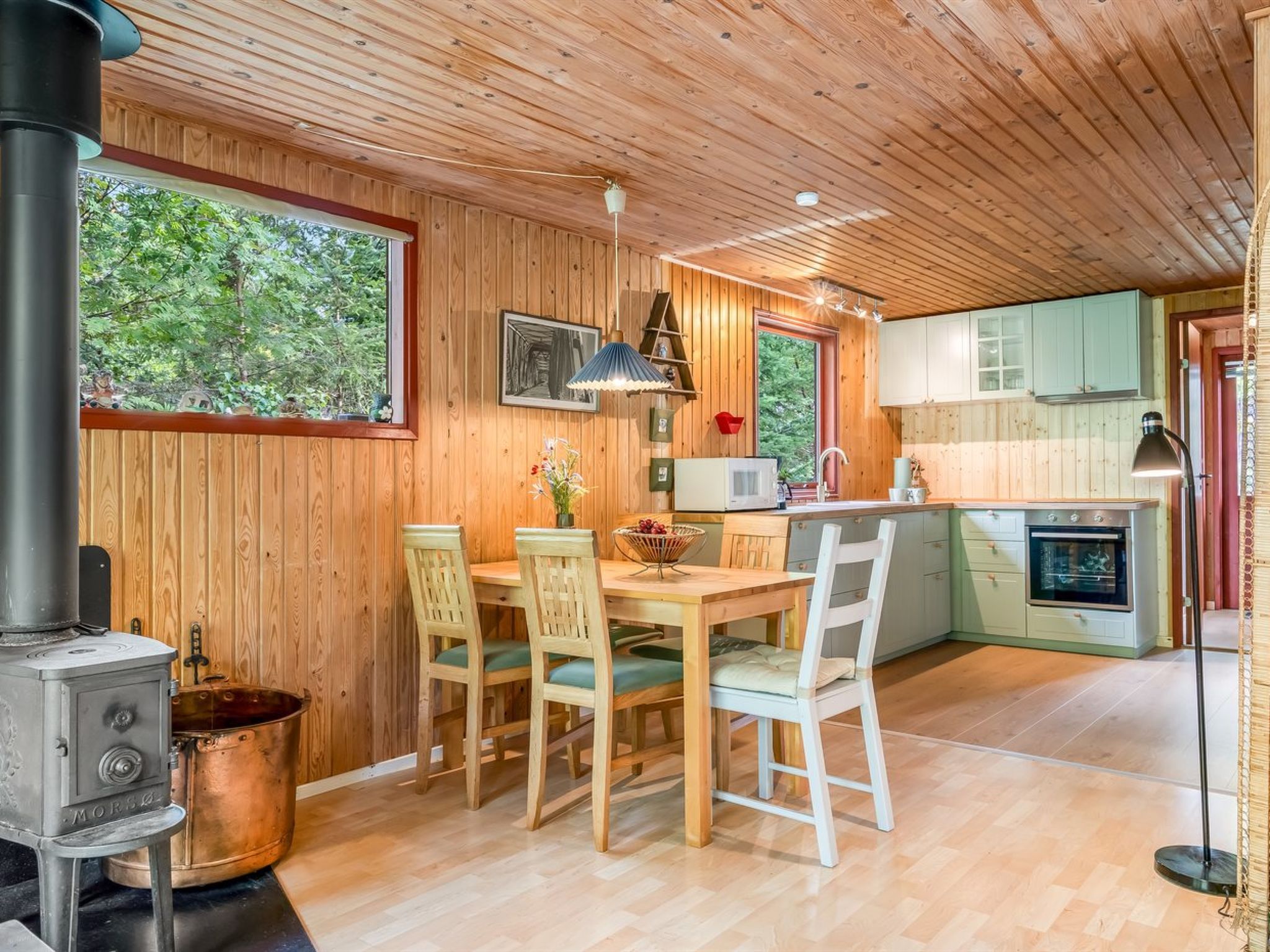 A wooden interior with a dining table, chairs, a stove, and a kitchen area.
