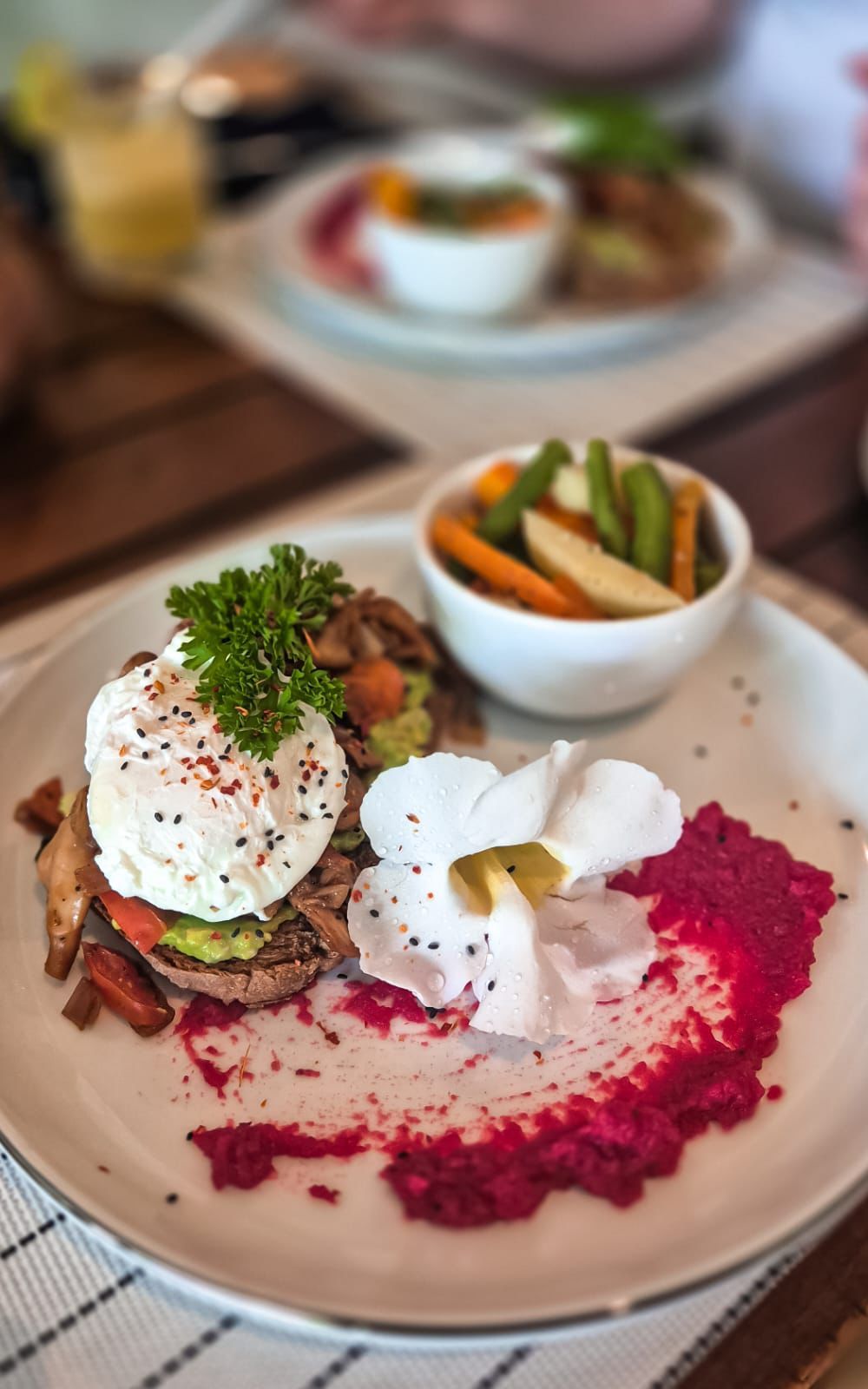 A plate with a salad, a poached egg, and a dollop of sauce.