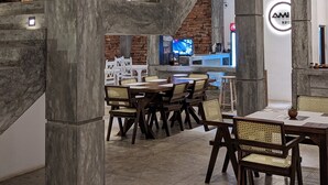 A modern interior with a central staircase, dining area with wooden tables and chairs, and a visible bar area with a television. - Ami Mirissa (Kamburugamuwa)