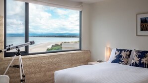 A bedroom with a large window offering a view of a beach and the sea. - Sea View - Freycinet Holiday Houses (Coles Bay)