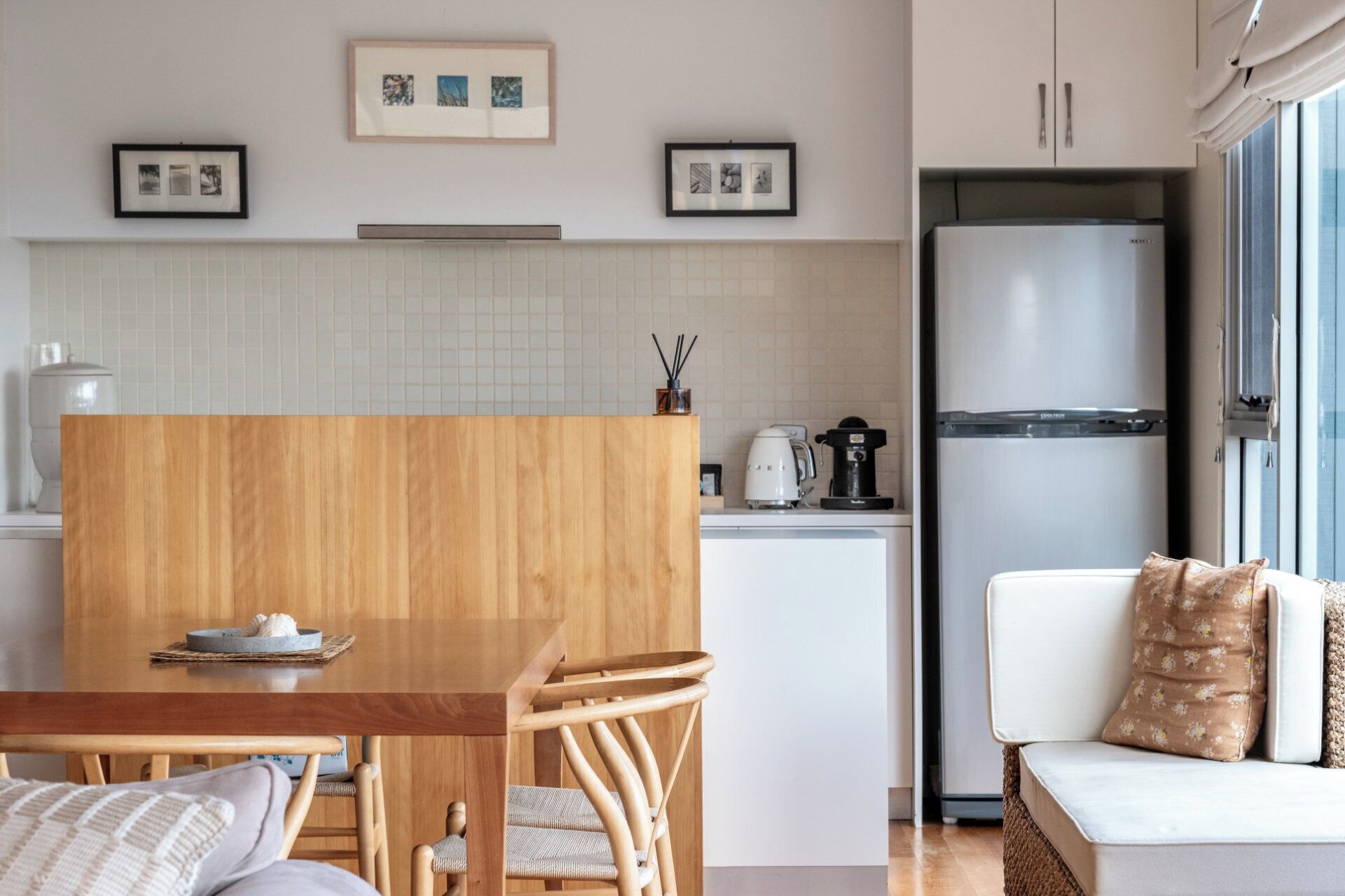 Een moderne keuken met een houten eettafel, witte kasten en een inbouwkoelkast.