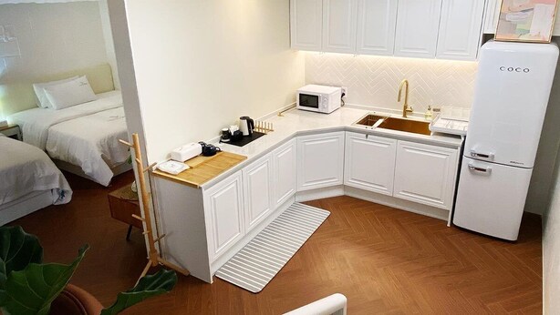 A compact hotel room with a kitchenette, a bed, and a small seating area. - 도심 가든풀빌라 이청정(利淸亭)
고층 독채스테이, 가족과의 도심여행
반려동물과의  휴식, 연인과의 추억, 친구들과의 풀파티 (Seoul)