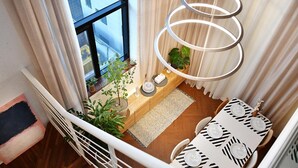 Un coin repas avec une table dressée pour quatre personnes, un luminaire suspendu et une vue sur la ville par la fenêtre.