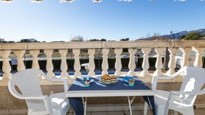 An outdoor patio with a table set for two, white plastic chairs, and a view of the sea and mountains in the background. - Miami Dorada II by Interhome (Miami Platja)