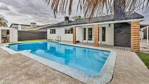 A modern house with a swimming pool, brick exterior, and a covered patio area. - Contemporary Modern Villa (Las Vegas)